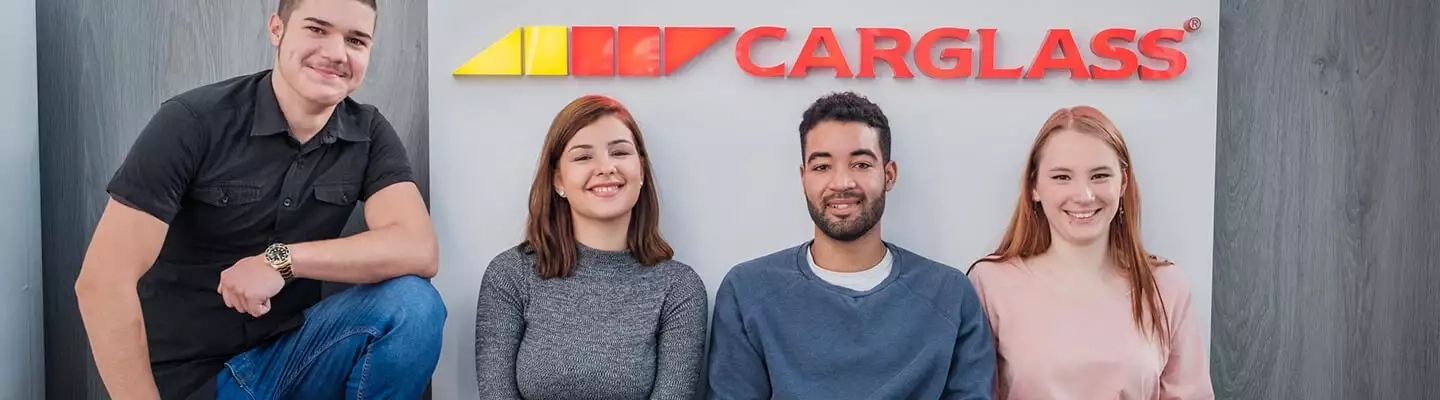 en.4 junge Menschen die vor einem Carglass<sup>®</sup>-Logo hocken