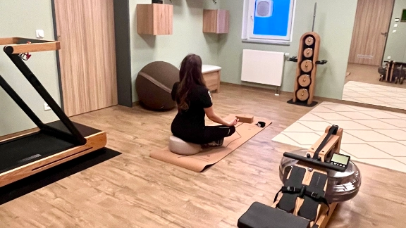 Sportraum mit Sportgeräten und Yogamatte. Person, die Yoga macht